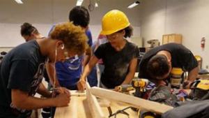 A group of women and men working to build something out of wood